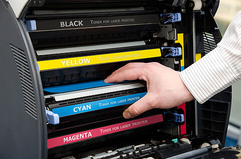 Ansicht der CMYK-Druckerpatronen im Drucker. Der Toner in Cyan wird gerade von eingesetzt.